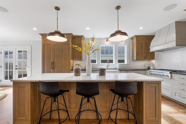 kitchen featuring white cabinetry, a kitchen island, custom exhaust hood, and pendant lighting