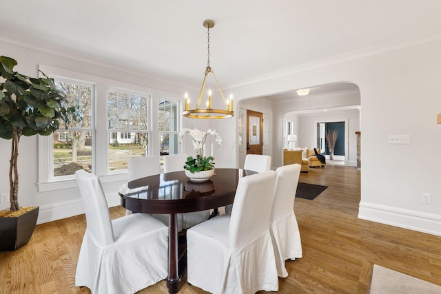 dining room with ornamental molding, wood-type flooring, and a notable chandelier