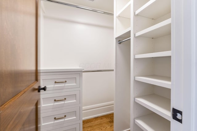 walk in closet with hardwood / wood-style flooring