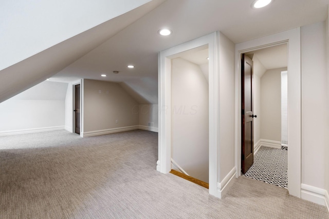 additional living space featuring vaulted ceiling and light colored carpet