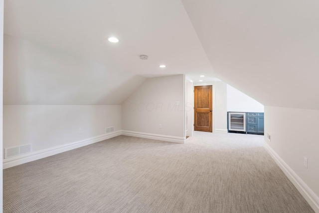 additional living space featuring vaulted ceiling and light carpet