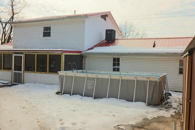 snow covered property featuring central AC and a sunroom