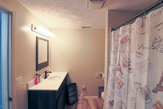 bathroom featuring vanity, hardwood / wood-style floors, a textured ceiling, and toilet