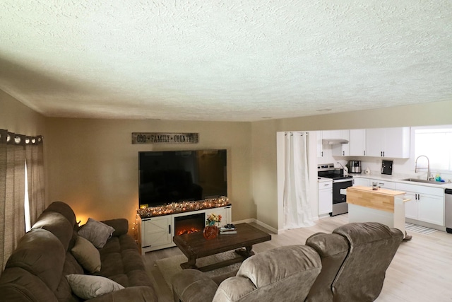 living room featuring sink, a textured ceiling, and light wood-type flooring