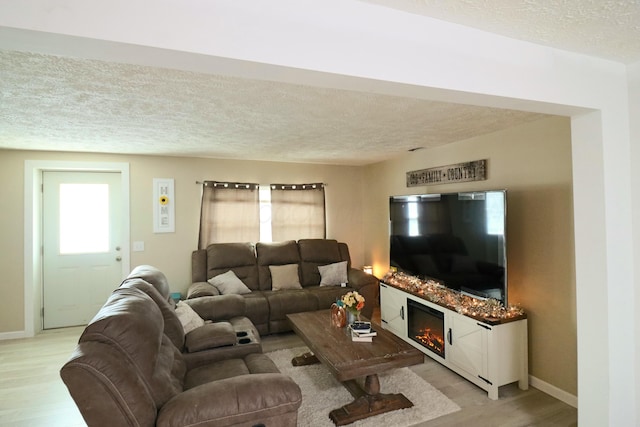 living room with plenty of natural light, a textured ceiling, and light wood-type flooring