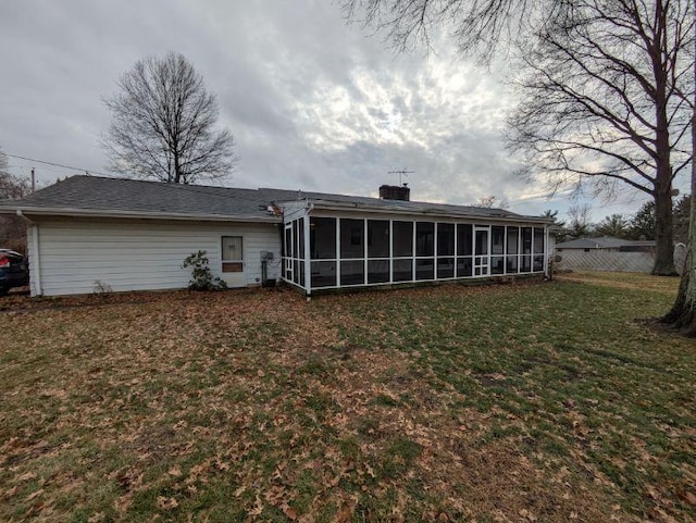 back of property with a sunroom and a lawn