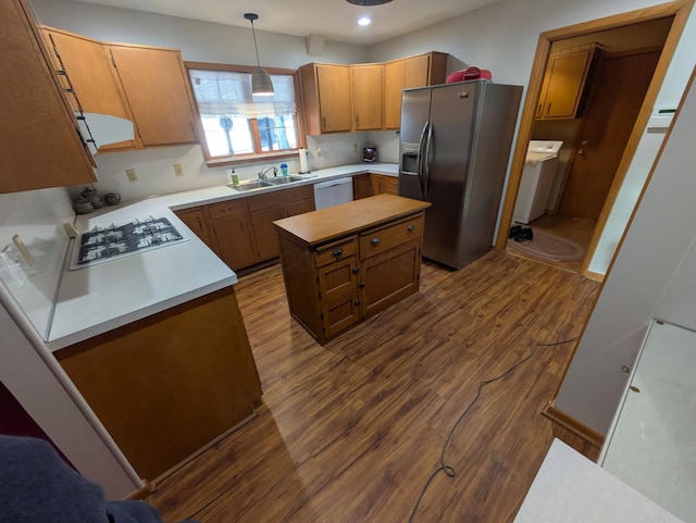 kitchen with sink, hanging light fixtures, hardwood / wood-style flooring, stainless steel appliances, and washer / clothes dryer