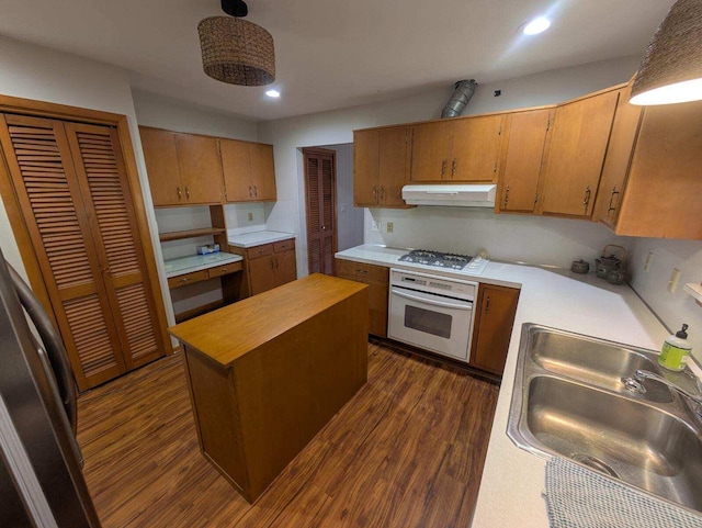 kitchen featuring dark wood-type flooring, sink, a center island, stainless steel gas stovetop, and white oven