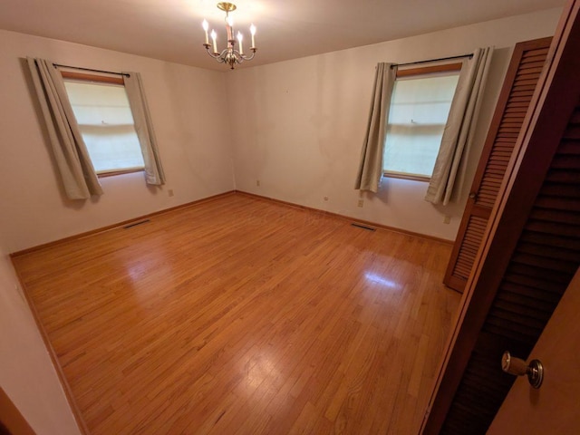 unfurnished room with a notable chandelier and light hardwood / wood-style floors