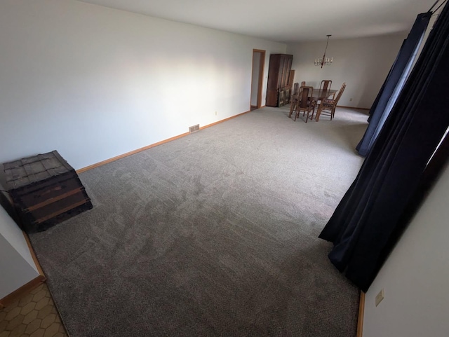 carpeted spare room with a chandelier