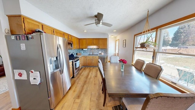 kitchen featuring a textured ceiling, light hardwood / wood-style flooring, appliances with stainless steel finishes, ceiling fan, and decorative backsplash