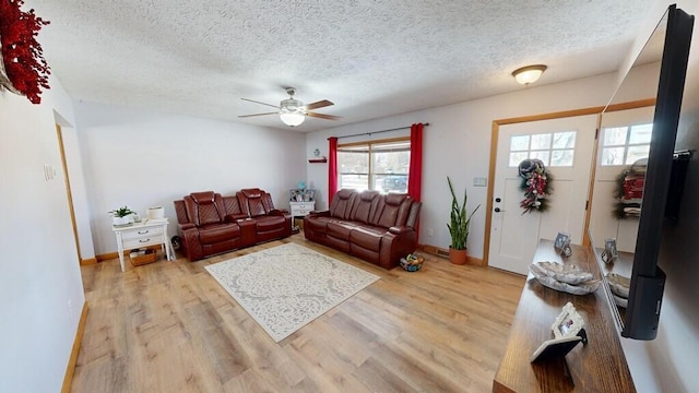 living room with ceiling fan, light hardwood / wood-style floors, and a textured ceiling