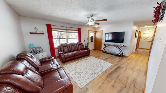 living room with ceiling fan, a textured ceiling, and light hardwood / wood-style floors