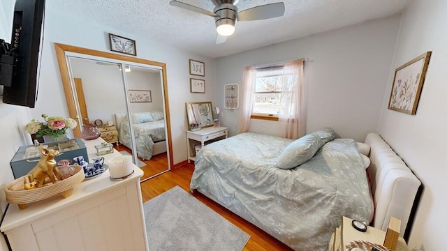 bedroom with light wood-type flooring, a textured ceiling, ceiling fan, and a closet