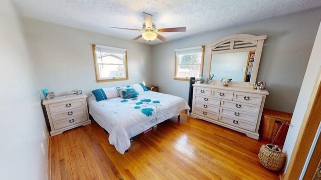 bedroom with light wood-type flooring, a textured ceiling, and ceiling fan