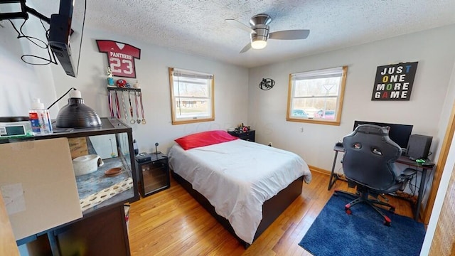 bedroom featuring multiple windows, light wood-type flooring, a textured ceiling, and ceiling fan