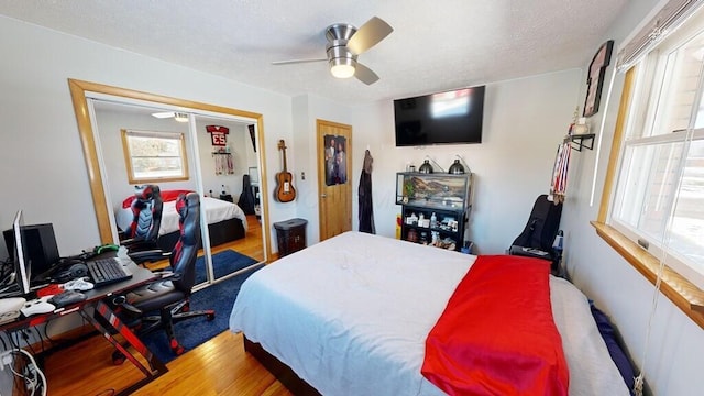 bedroom with hardwood / wood-style floors, a textured ceiling, ceiling fan, and a closet