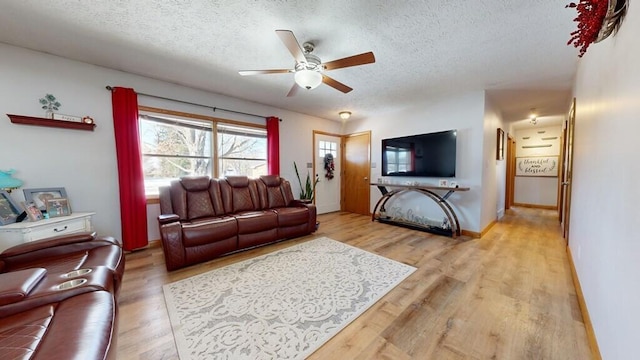 living room with ceiling fan, wood-type flooring, and a textured ceiling