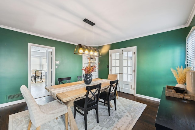 dining area featuring dark wood-type flooring, ornamental molding, and french doors