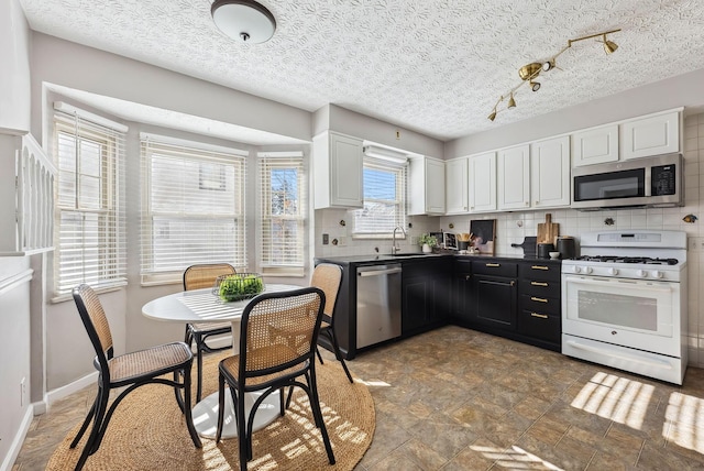 kitchen featuring tasteful backsplash, sink, white cabinets, and appliances with stainless steel finishes