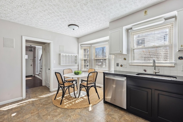 kitchen with tasteful backsplash, white cabinetry, sink, stainless steel dishwasher, and a textured ceiling