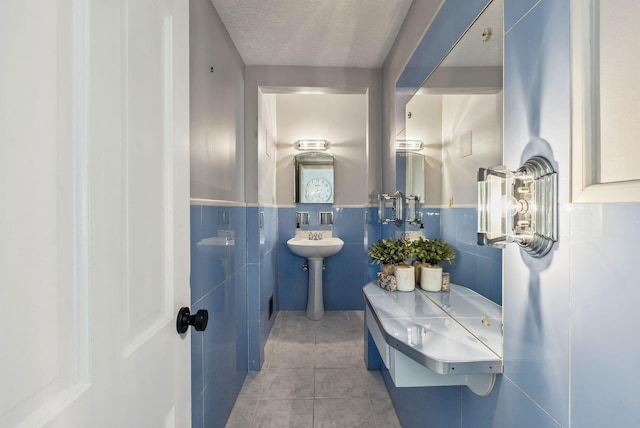 bathroom featuring tile walls, tile patterned flooring, and a textured ceiling