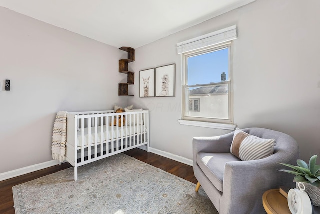 bedroom with dark hardwood / wood-style flooring and a nursery area