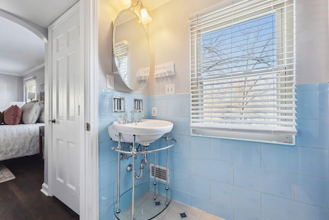 bathroom featuring ornamental molding, sink, wood-type flooring, and tile walls