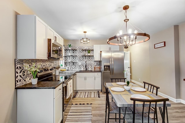 kitchen featuring an inviting chandelier, stainless steel appliances, hanging light fixtures, and white cabinets