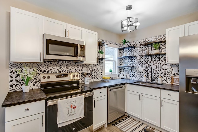 kitchen featuring pendant lighting, appliances with stainless steel finishes, sink, and white cabinets