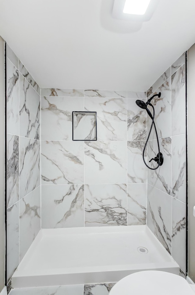 bathroom featuring toilet and a tile shower