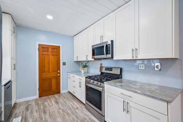 kitchen with light stone countertops, white cabinetry, appliances with stainless steel finishes, and tasteful backsplash