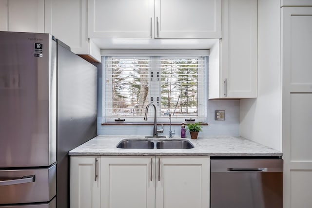 kitchen with sink, light stone countertops, white cabinets, and appliances with stainless steel finishes