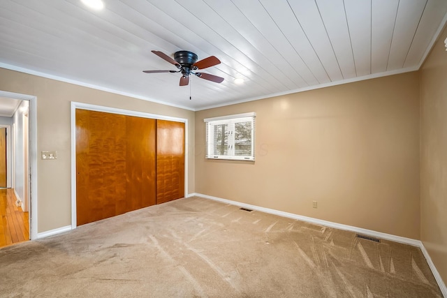 unfurnished bedroom with ceiling fan, ornamental molding, carpet floors, and a closet