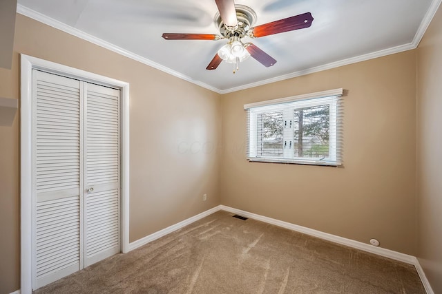 unfurnished bedroom featuring crown molding, ceiling fan, carpet, and a closet