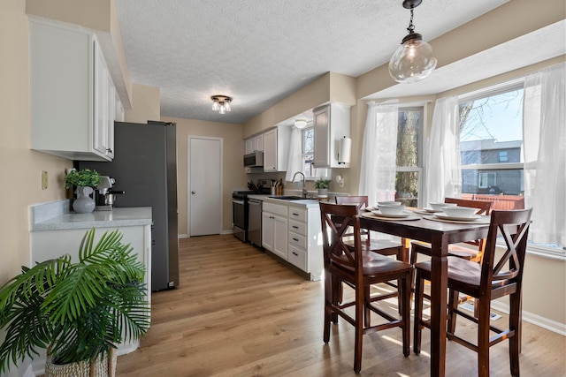 kitchen with a healthy amount of sunlight, appliances with stainless steel finishes, sink, and white cabinets