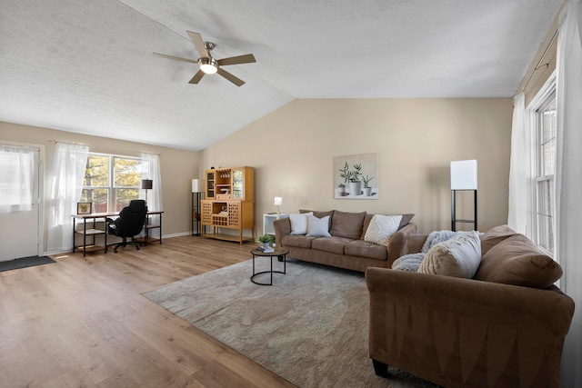 living room featuring lofted ceiling, light hardwood / wood-style floors, and ceiling fan