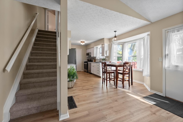 interior space featuring hardwood / wood-style flooring, vaulted ceiling, sink, and a textured ceiling