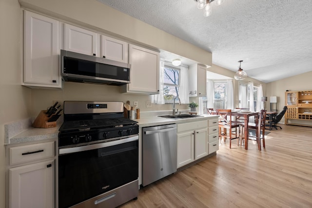 kitchen featuring stainless steel appliances, vaulted ceiling, sink, and white cabinets