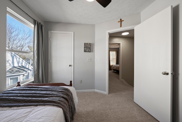 carpeted bedroom featuring multiple windows, a textured ceiling, and ceiling fan