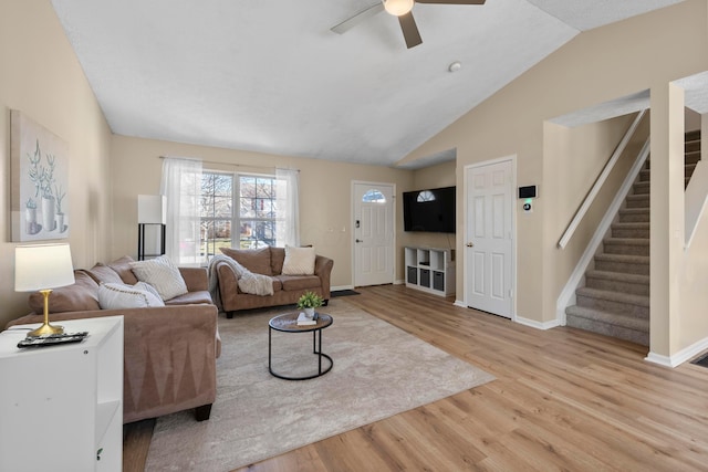 living room with vaulted ceiling, ceiling fan, and light wood-type flooring