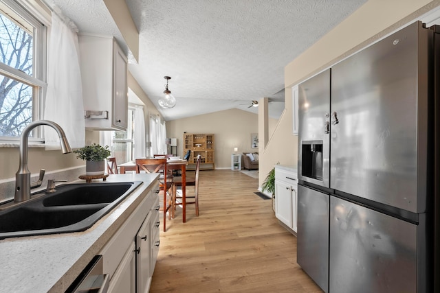 kitchen featuring lofted ceiling, sink, stainless steel fridge, a textured ceiling, and white cabinets