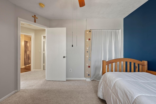 bedroom with ceiling fan, light colored carpet, and a textured ceiling