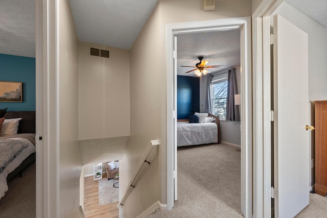 carpeted bedroom with ceiling fan and a textured ceiling