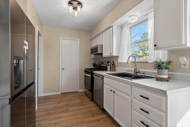 kitchen featuring white cabinetry, sink, light wood-type flooring, and appliances with stainless steel finishes