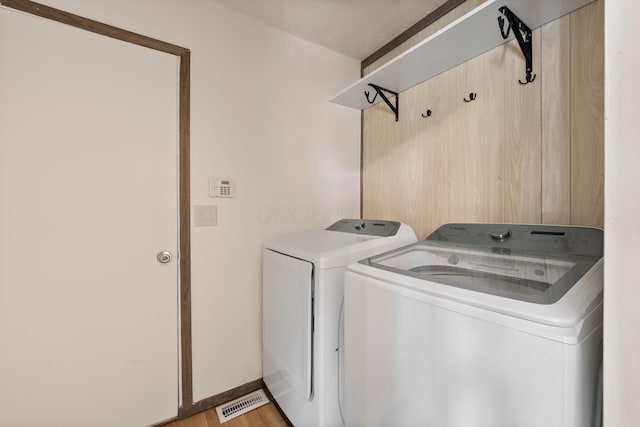 washroom with independent washer and dryer, a textured ceiling, and light wood-type flooring