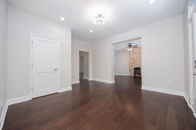 unfurnished living room featuring ceiling fan, a fireplace, and dark hardwood / wood-style flooring