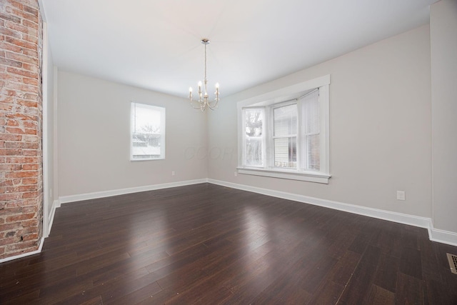 spare room with an inviting chandelier, plenty of natural light, and dark hardwood / wood-style floors