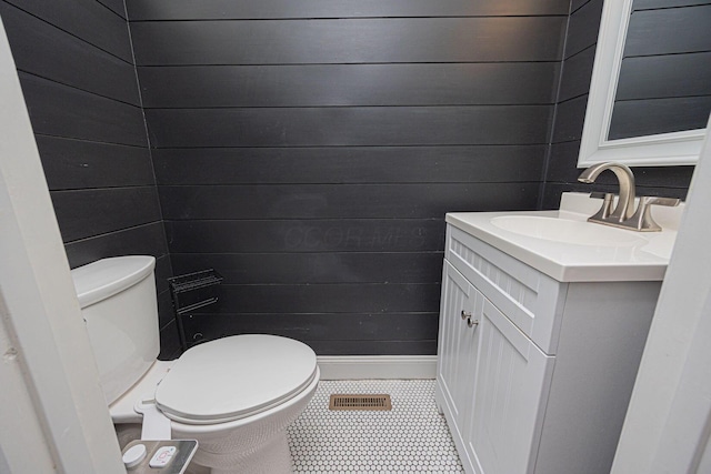 bathroom featuring vanity, wooden walls, and toilet