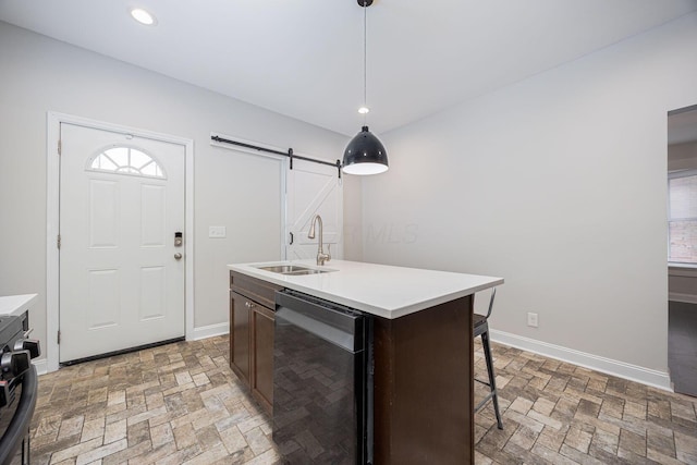 kitchen with pendant lighting, sink, dishwasher, an island with sink, and a barn door